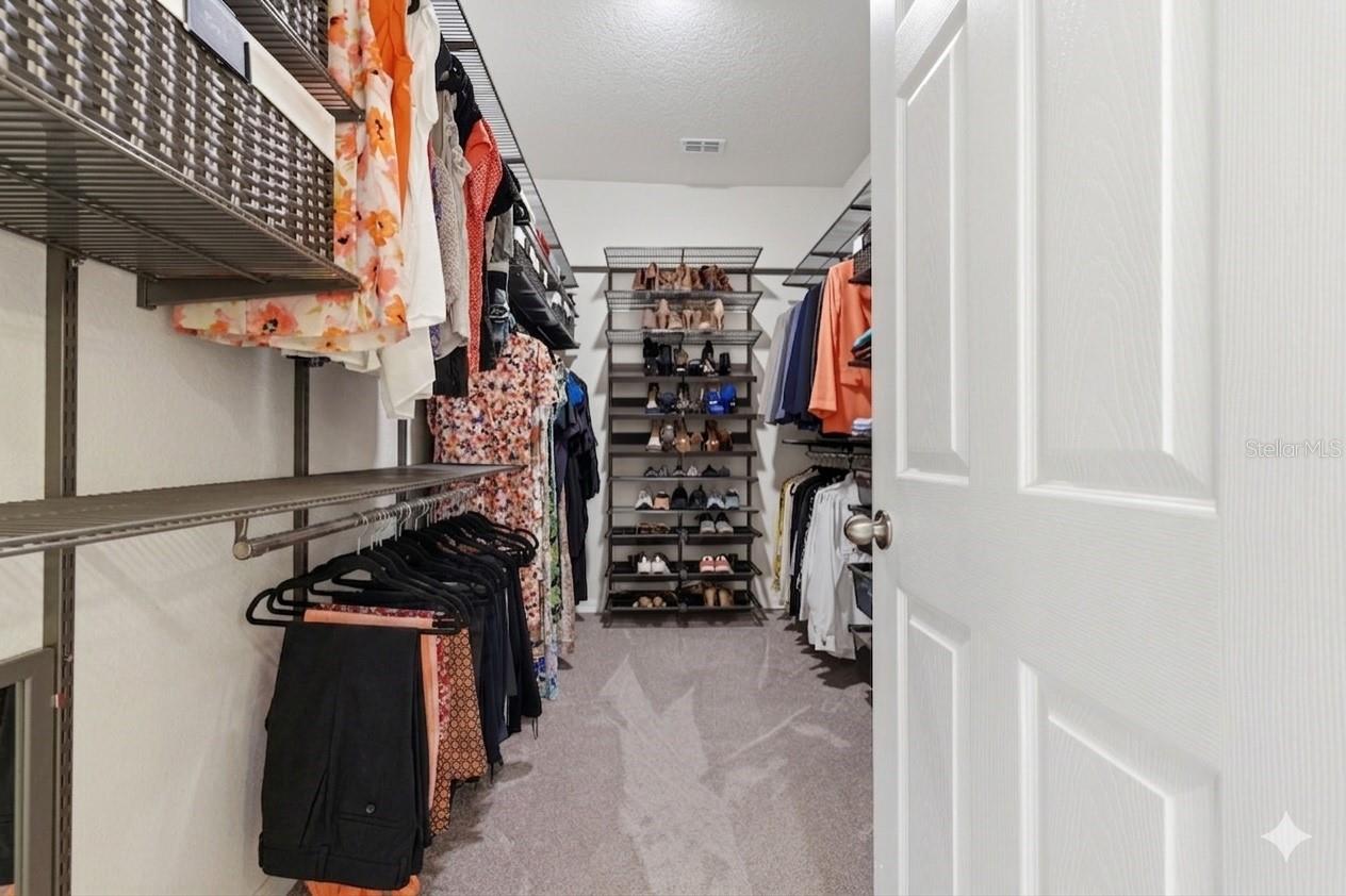 Primary bedroom's walk in closet with custom organizers