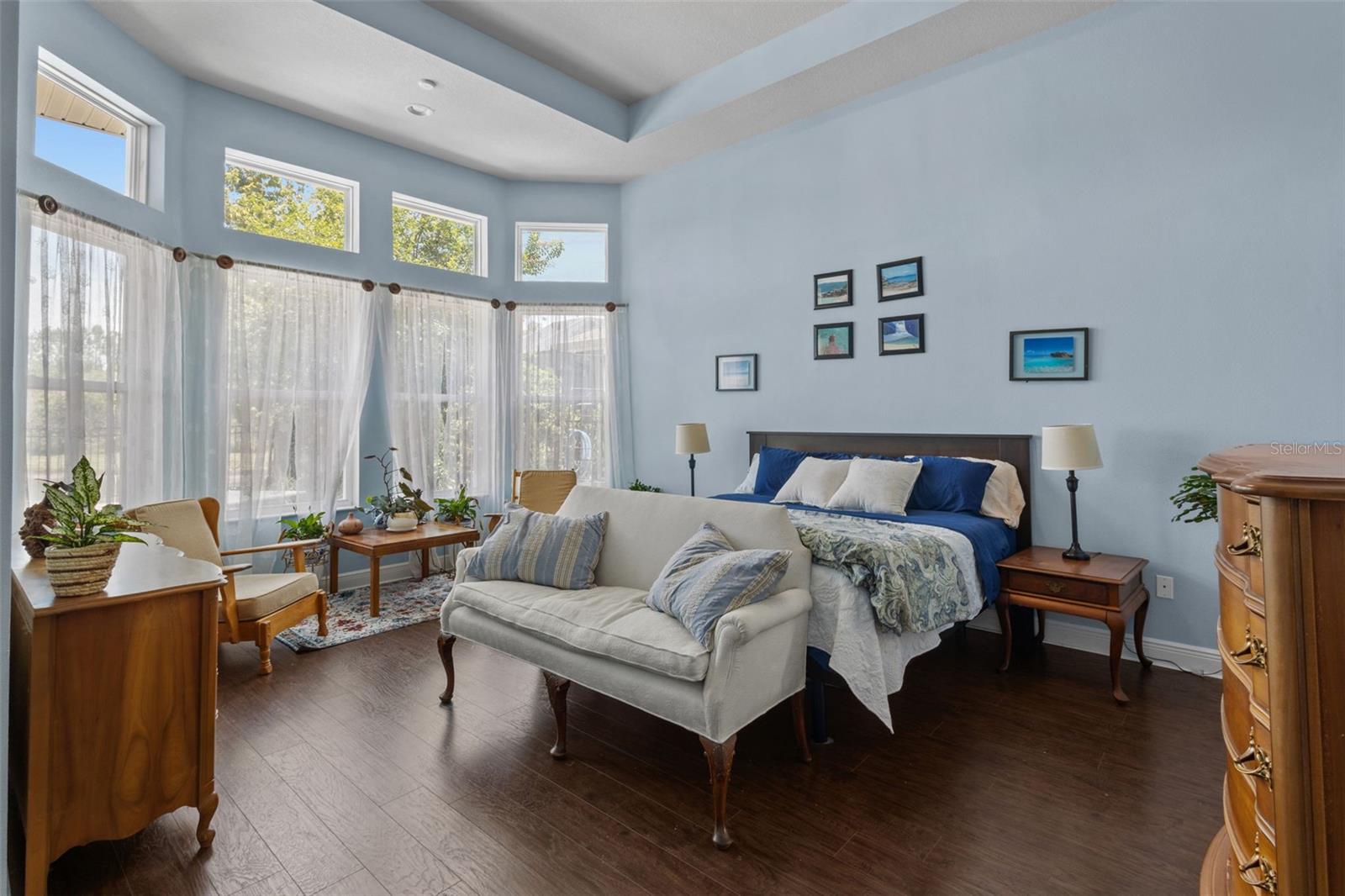 Primary bedroom features soaring ceilings, bay window, and upgraded laminate flooring
