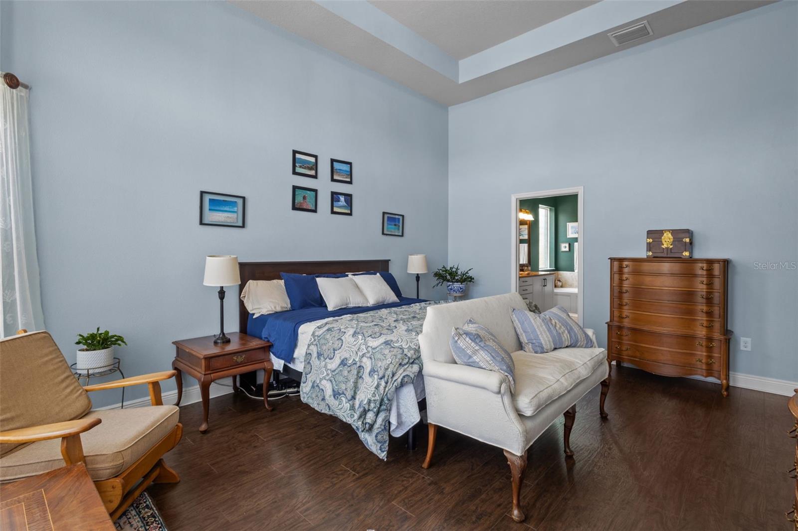 Primary bedroom features soaring ceilings, bay window, and upgraded laminate flooring