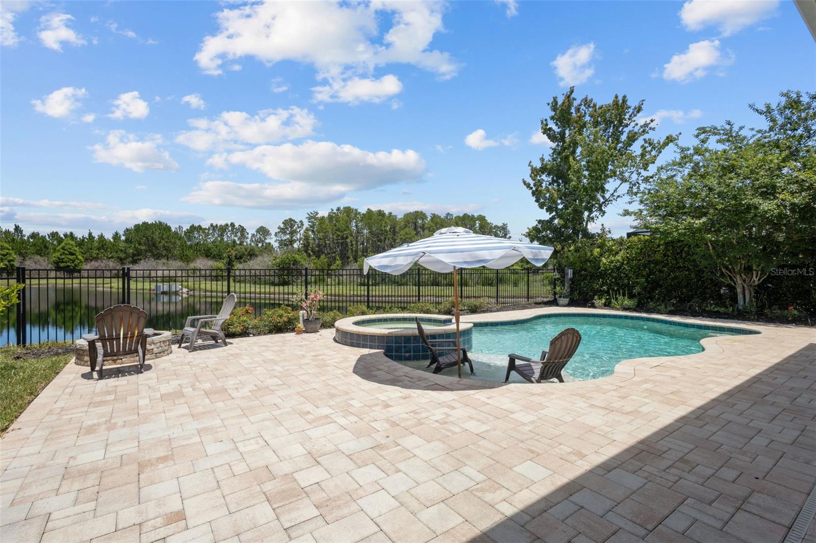 Backyard features pool, spa, fire pit, covered patio, and scenic water views