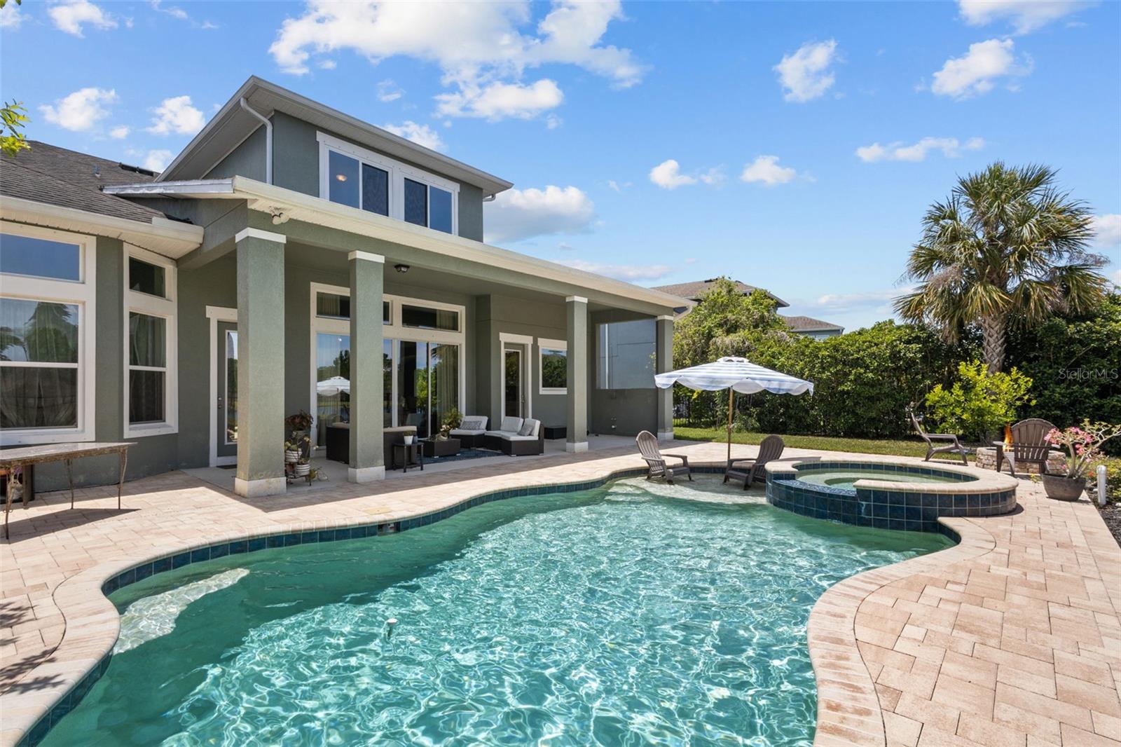 Pool features a sun shelf, spa, and paver patio overlooking the pond.
