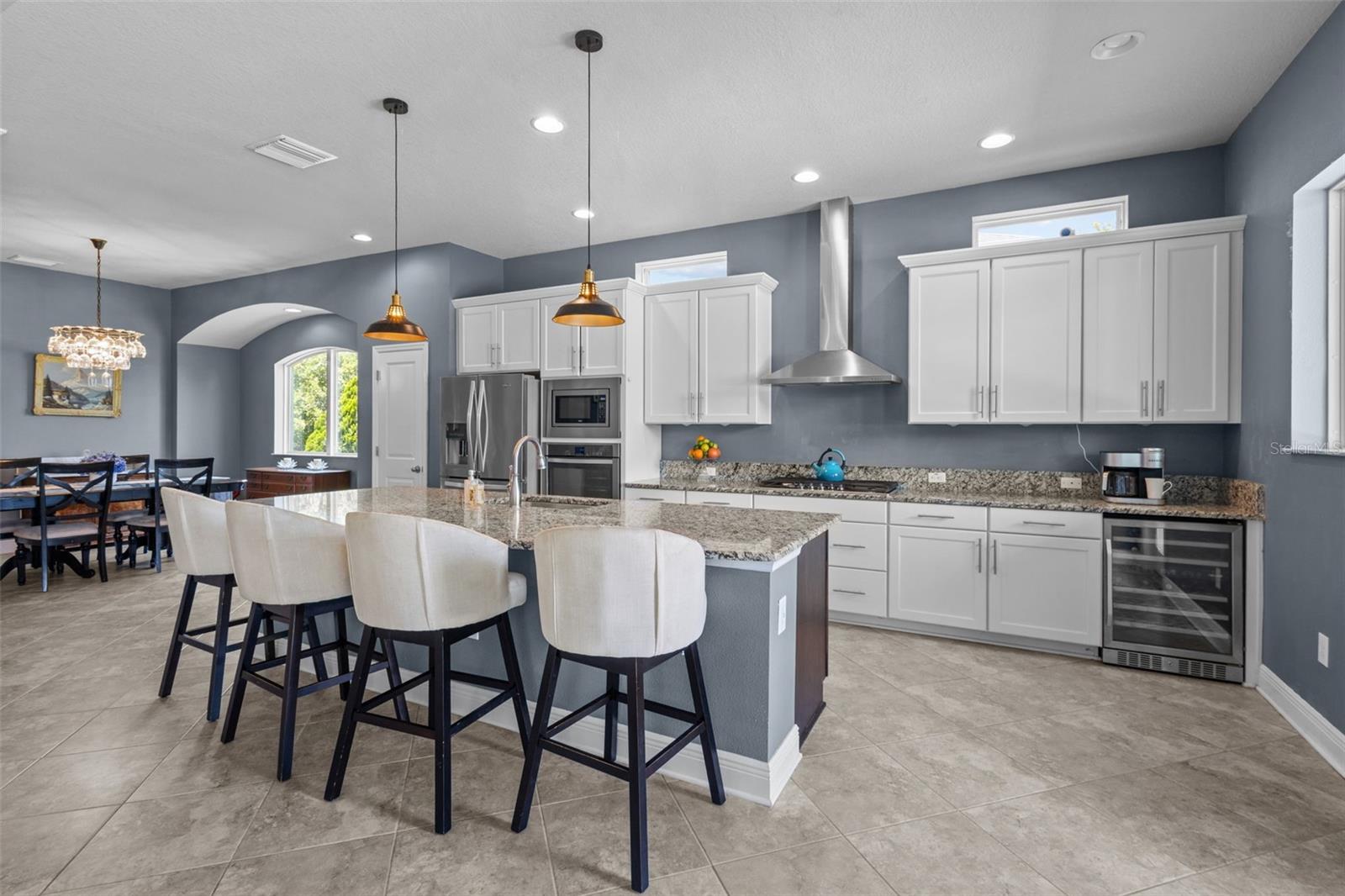 Spacious kitchen with granite countertops, built-in stainless steel appliances, and wine fridge