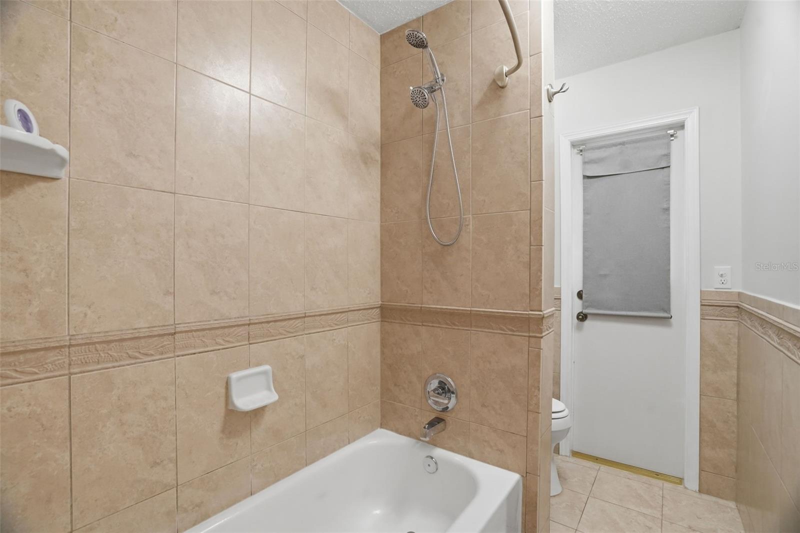 Shower, toilet and door to backyard in guest bathroom
