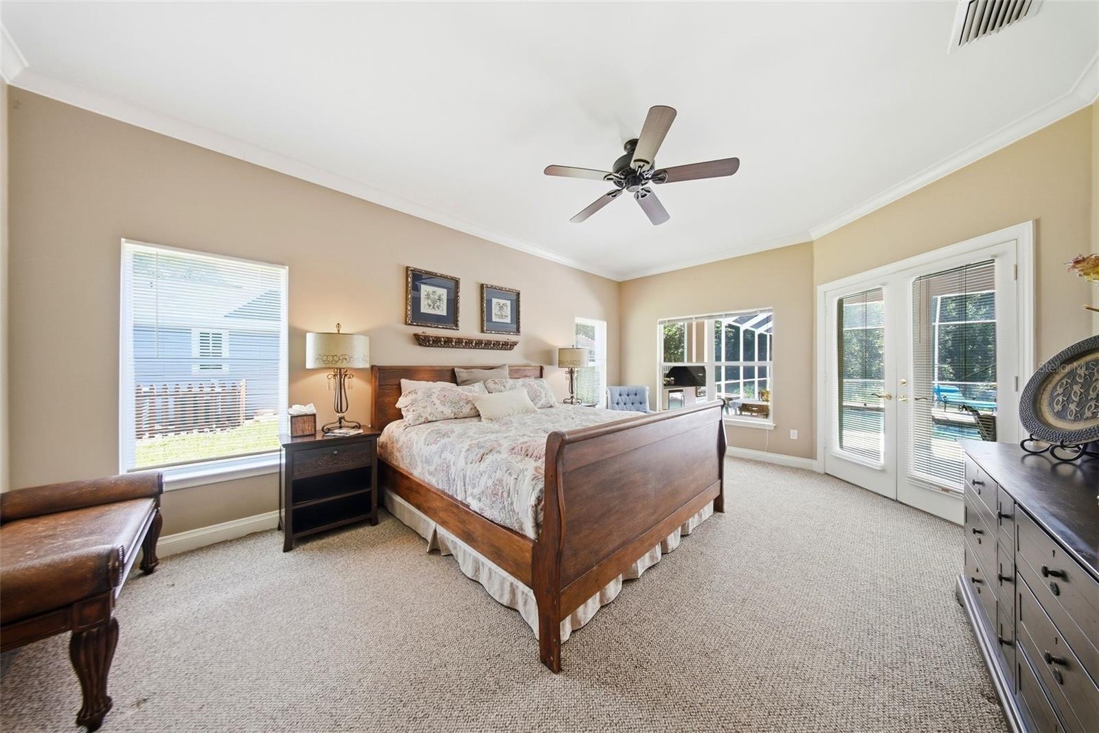 Large primary bedroom with french doors leading to the pool area.