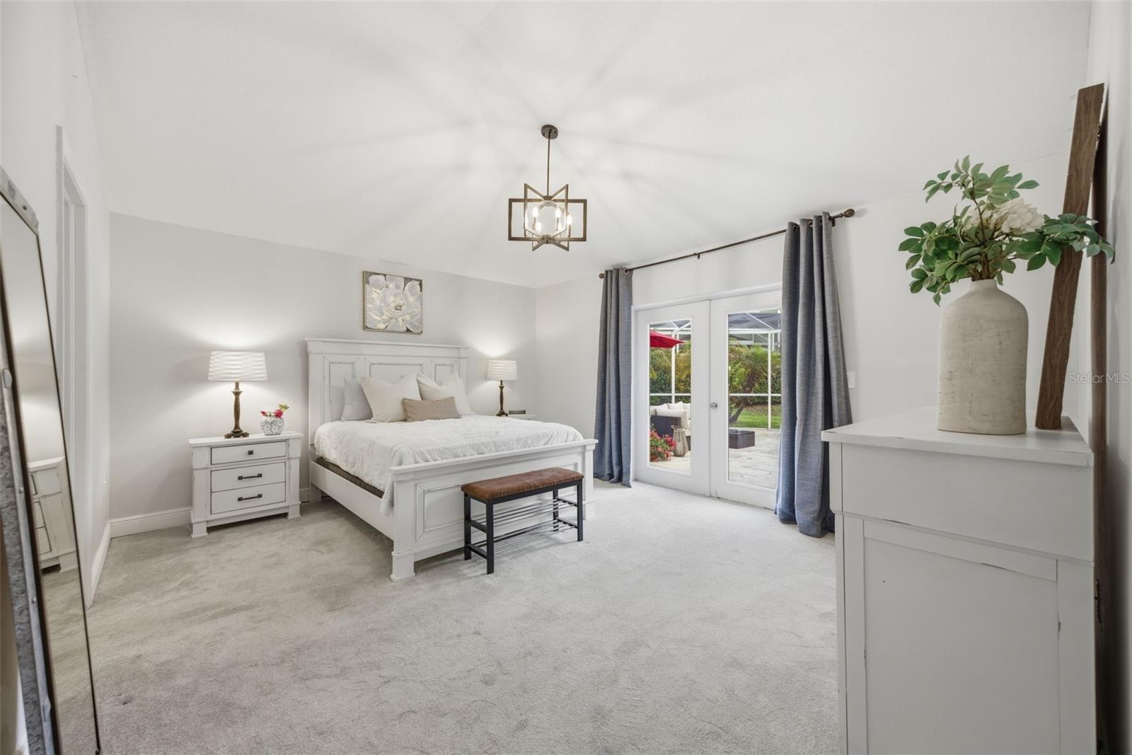 spacious primary suite with french door to your pool deck and screened lanai