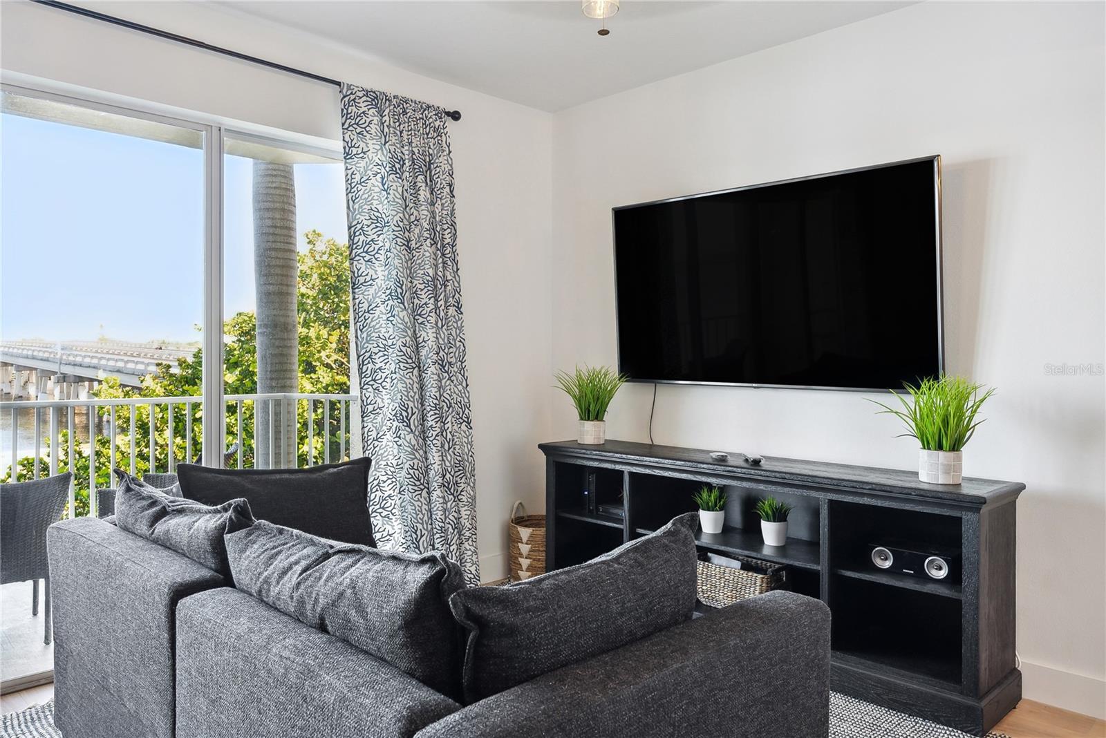 View of Living room with Leather pull-out sleeper sofa, mounted smart TV and storage cabinet, luxury vinyl flooring throughout and custom blackout temperature reducing drapes