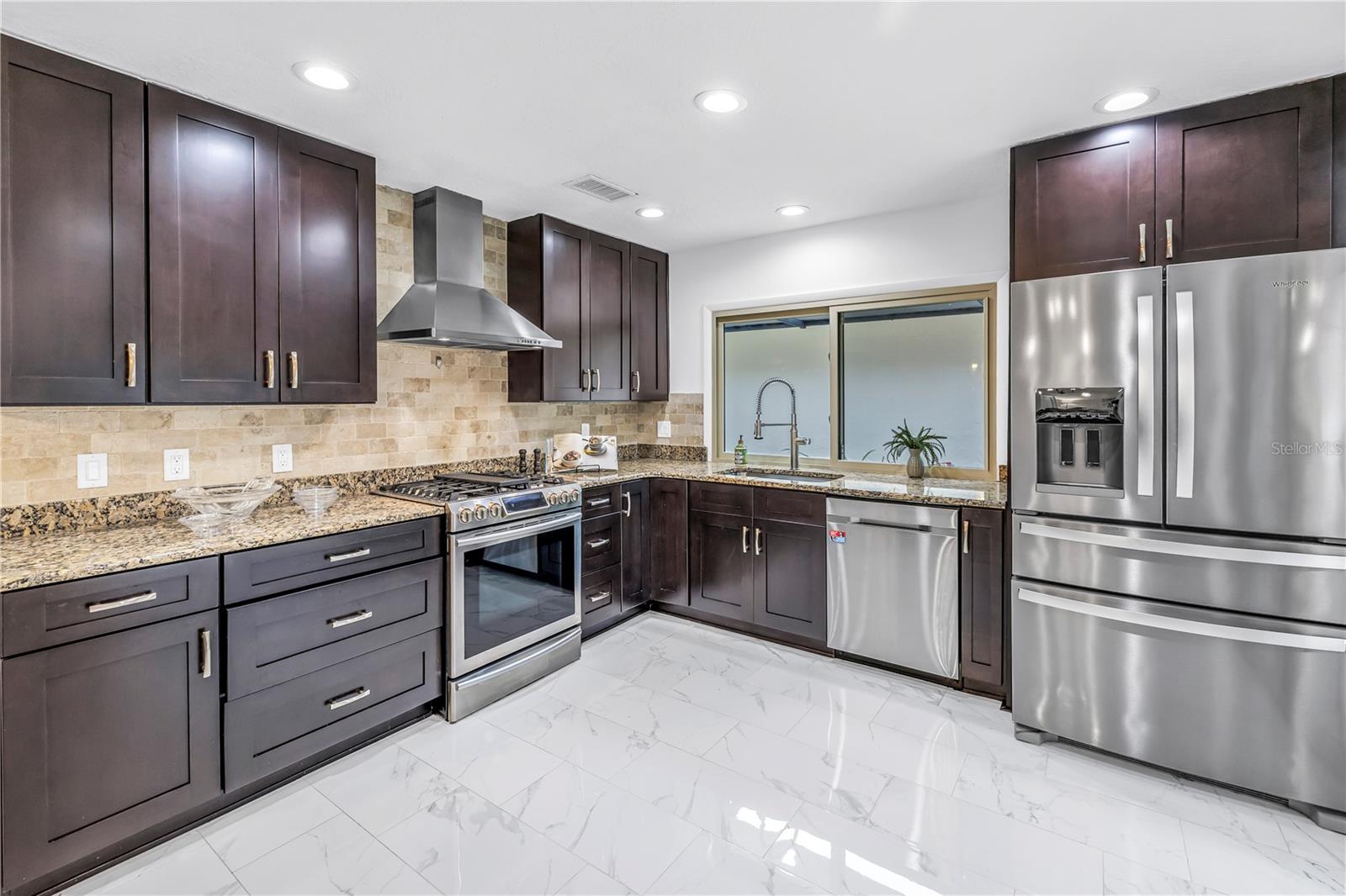 Full Granite and Stainless Kitchen is Spacious with bar to entertain and hurricane impact sliders to the lanai