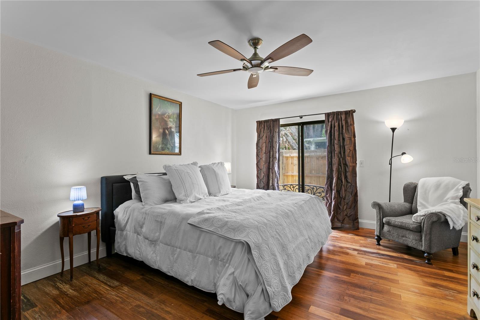 Primary suite with hard wood flooring and sliding door to side patio