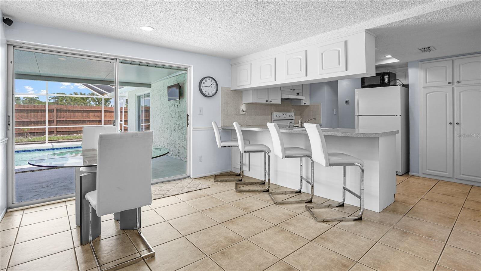 Dining and kitchen overlooking enclosed lanai and pool.