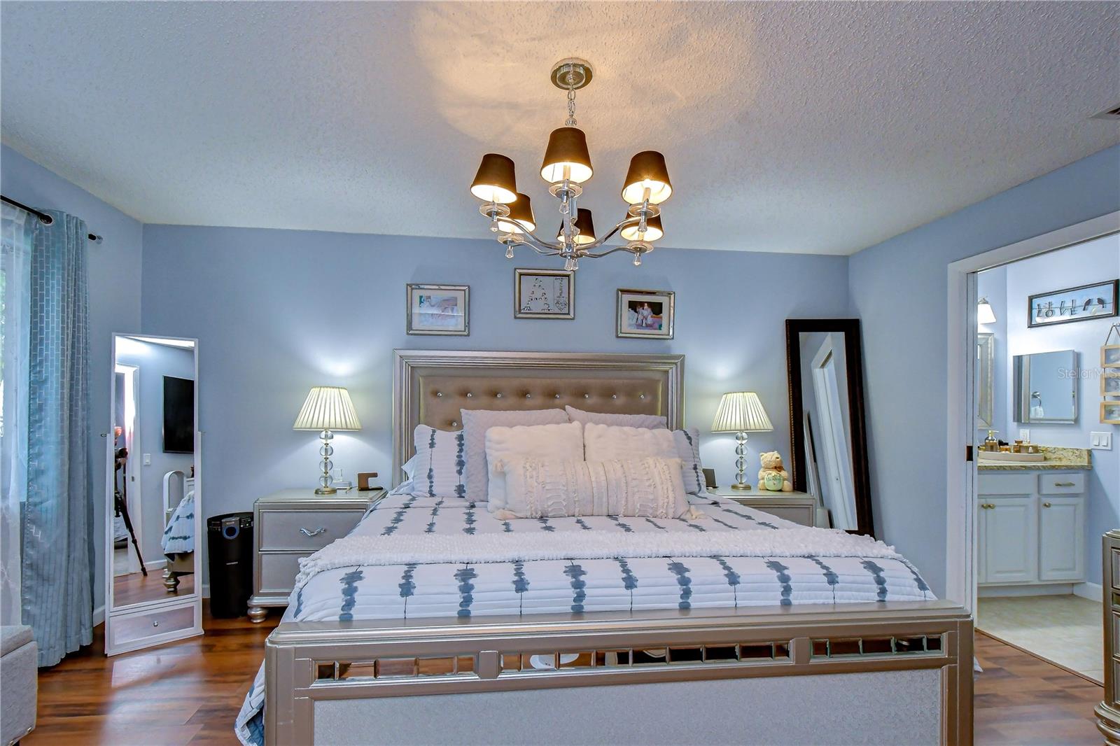 Primary bedroom is spacious with inviting lighting and upgraded flooring