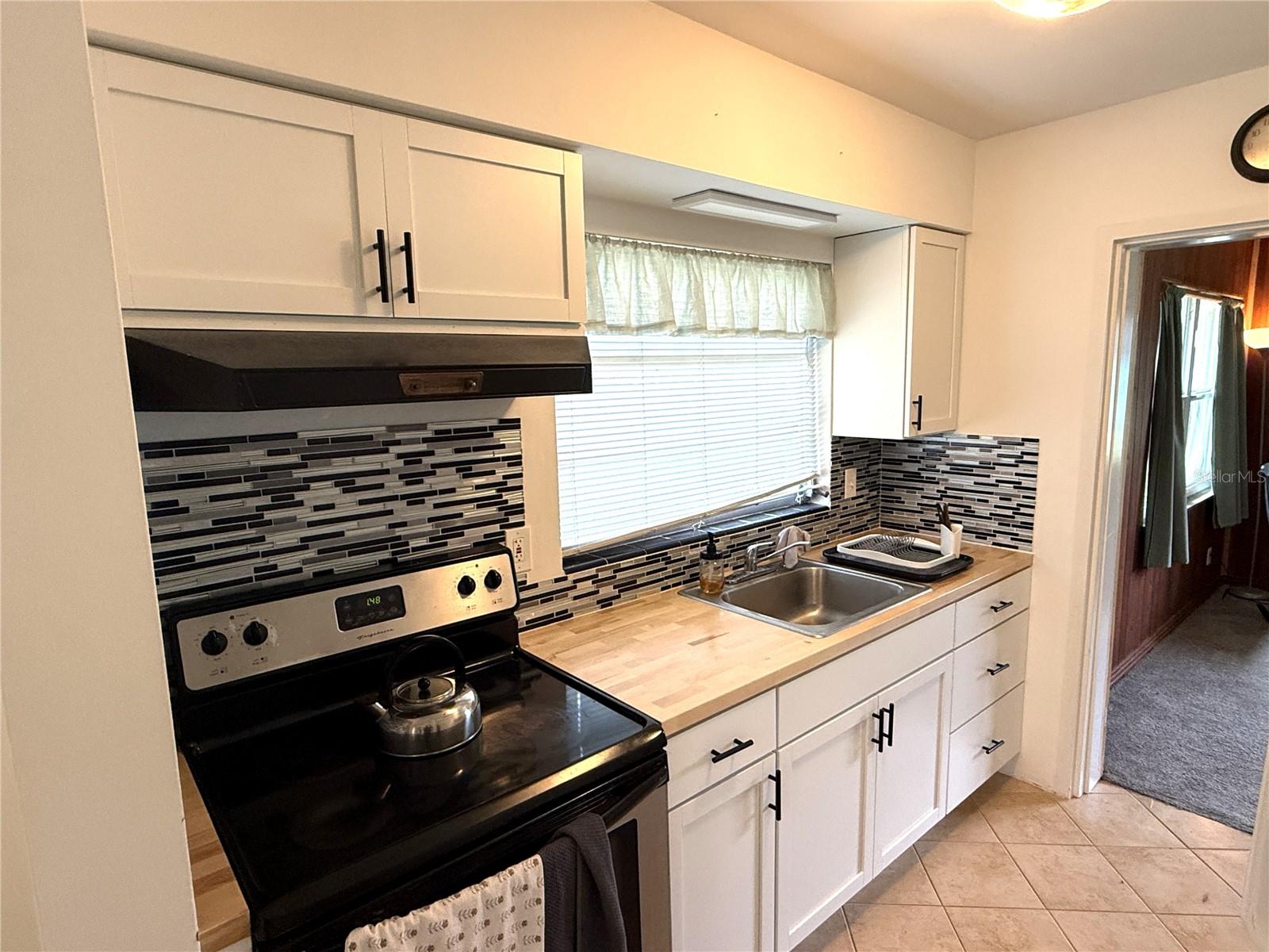 Kitchen with newer cabinets, backsplash and butcher block top