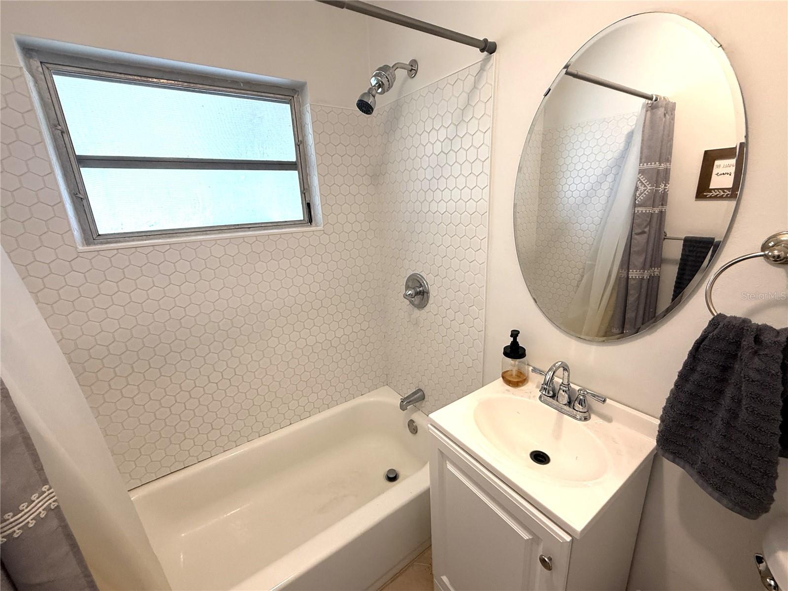Newer toilet, vanity, mirror and tile surround.