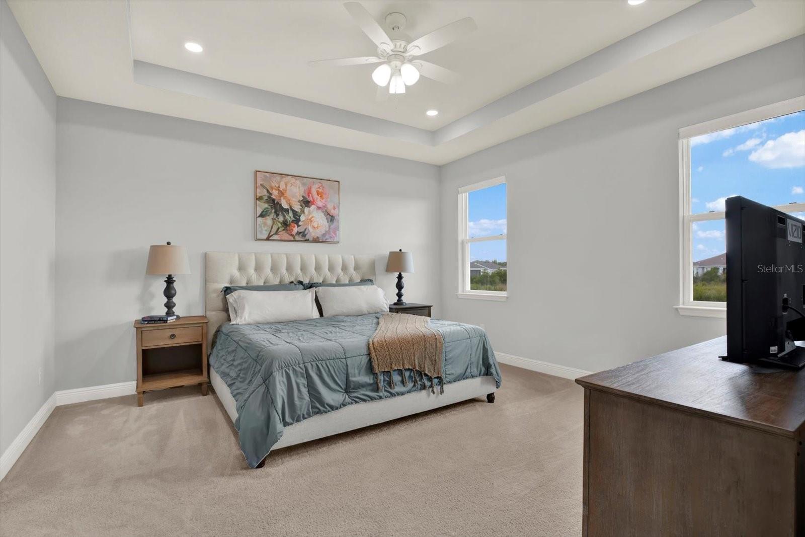Primary bedroom includes tray ceiling and ceiling fan