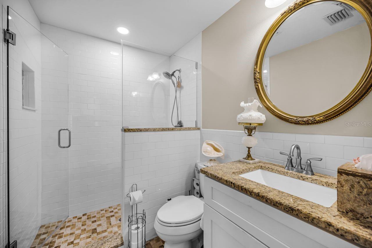 Walk-in shower, granite top and tiled flooring.