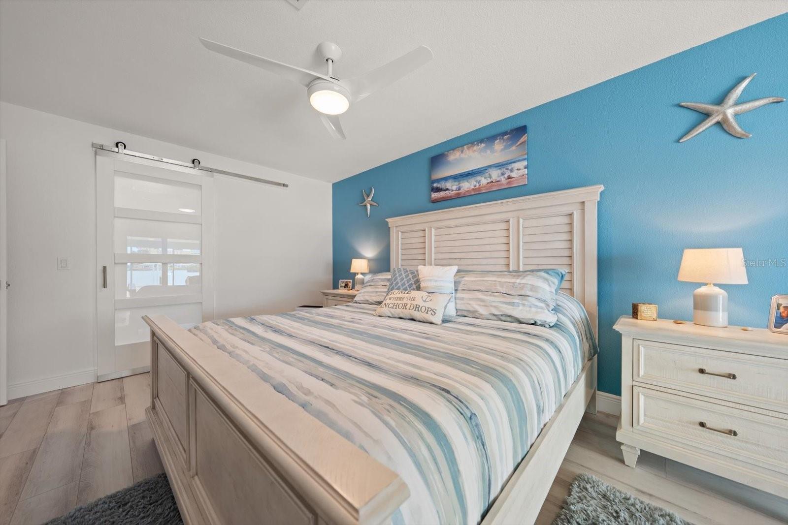 Spacious primary bedroom featuring a king-size bed with an adjustable power base frame and elegant barn door access to the ensuite bathroom.
