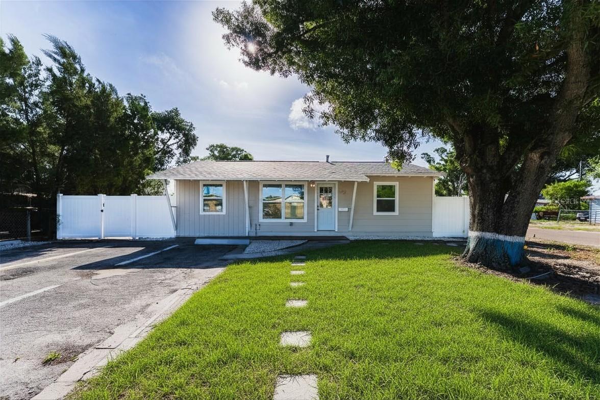 Nestled beneath mature shade trees, this updated ranch offers a lush front yard, white vinyl privacy fence, and a stepping stone walkway leading to the front entry. New paint, windows, and updated exterior finishes make this home truly move-in ready. (Lawn digitally enhanced for illustrative purposes.)