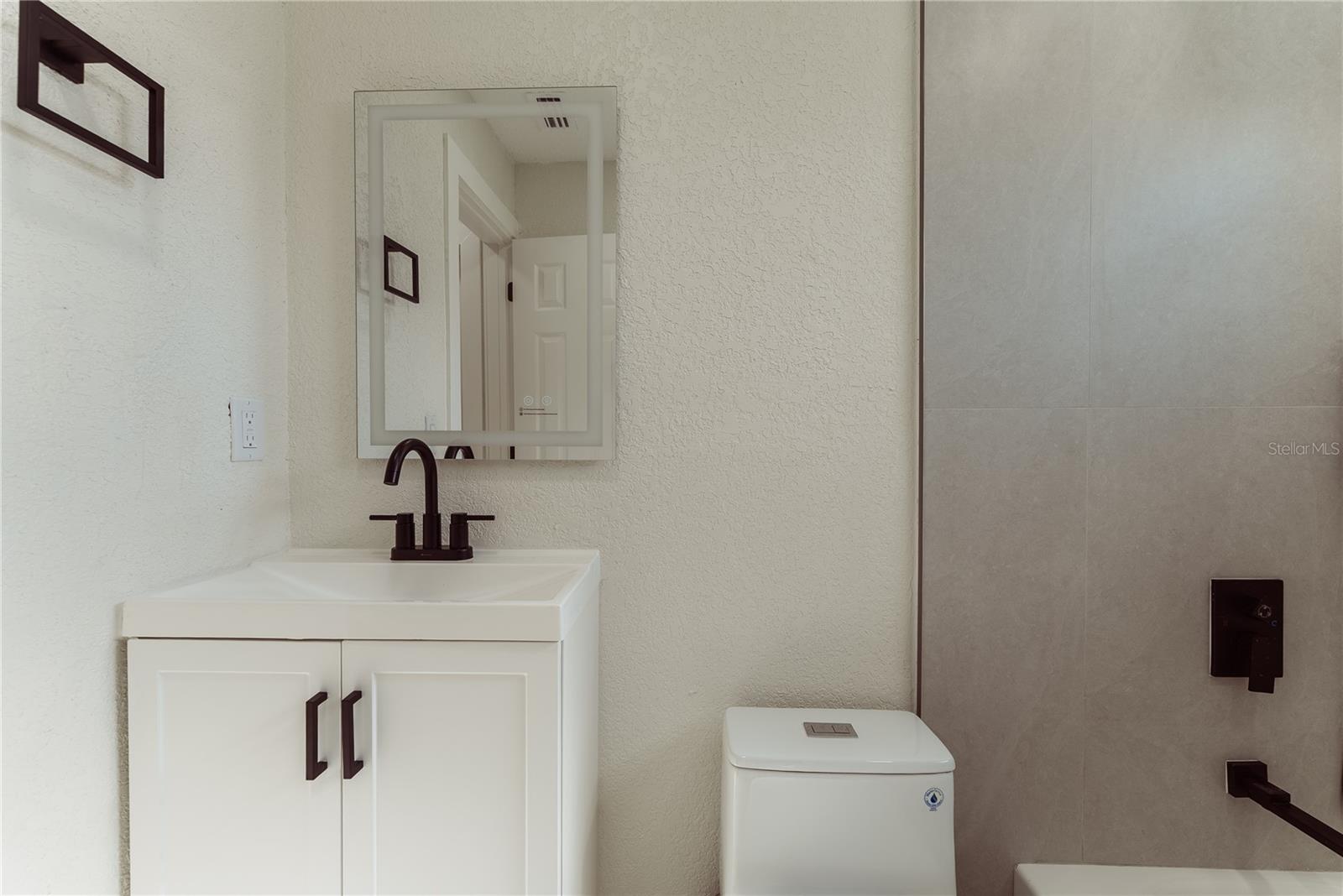 Every finish in the second bath is new, from the white shaker vanity and matte black faucet to the framed mirror and floor-to-ceiling tile surround surrounding the tub/shower combo.