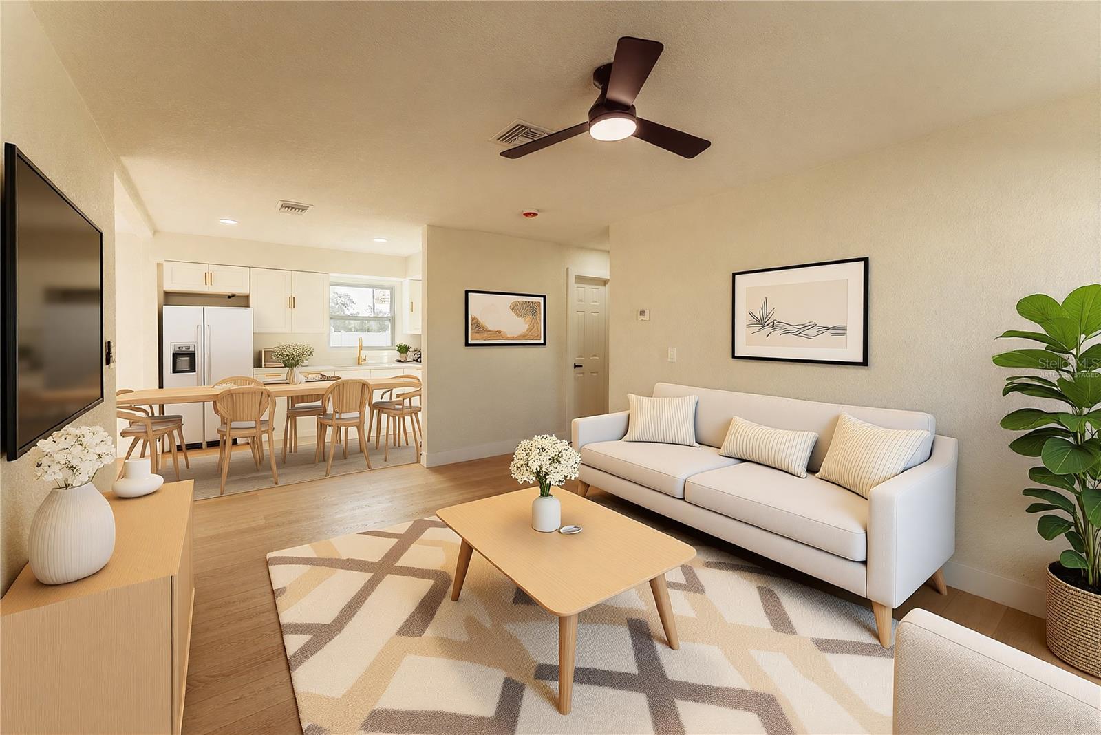 The open-concept floor plan shines in this view, showcasing the seamless flow from the living area into the dining space and kitchen beyond. Warm luxury vinyl flooring, recessed lighting, and a modern ceiling fan carry throughout, while the updated kitchen with white cabinetry and a stainless steel appliance package to be provided — perfect for everyday living and entertaining. (Virtually Staged.)