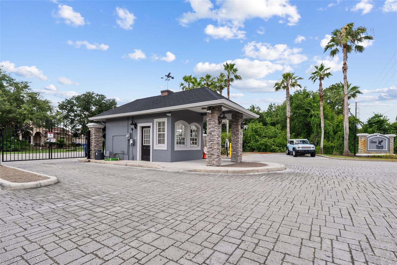 Guard-gated community entrance with pavered drive and secure access.