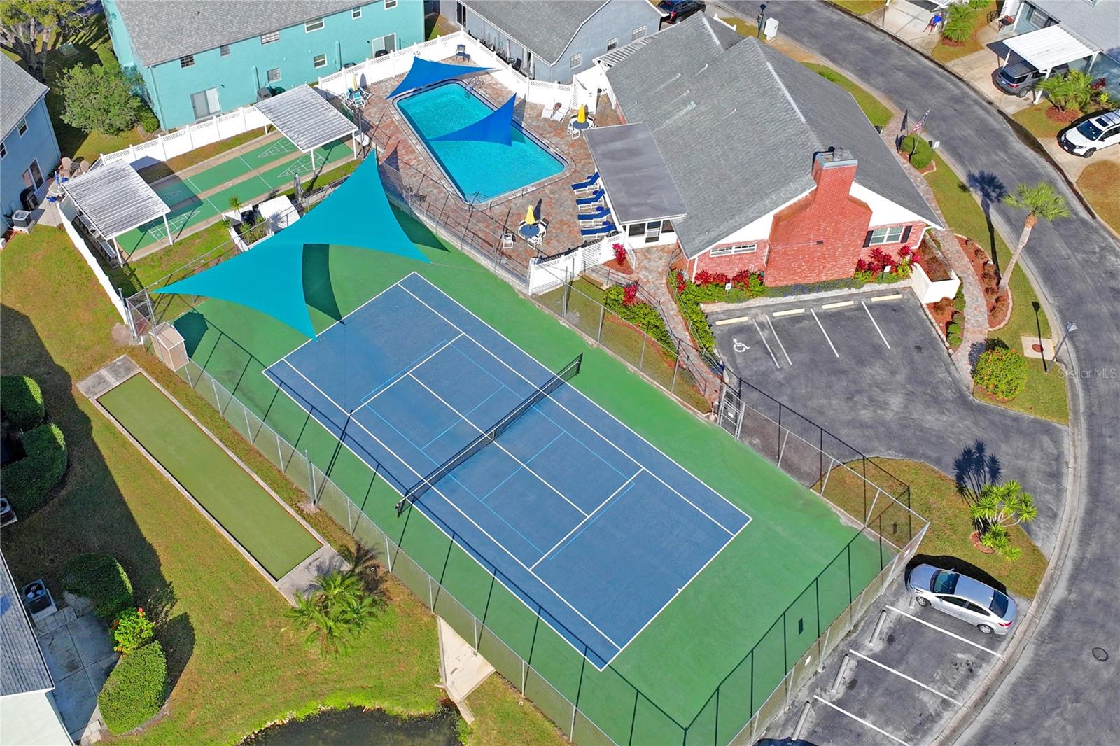 Aerial view of the amenities at The Wilds includes tennis courts, a heated pool, shuffleboard, and bocce.