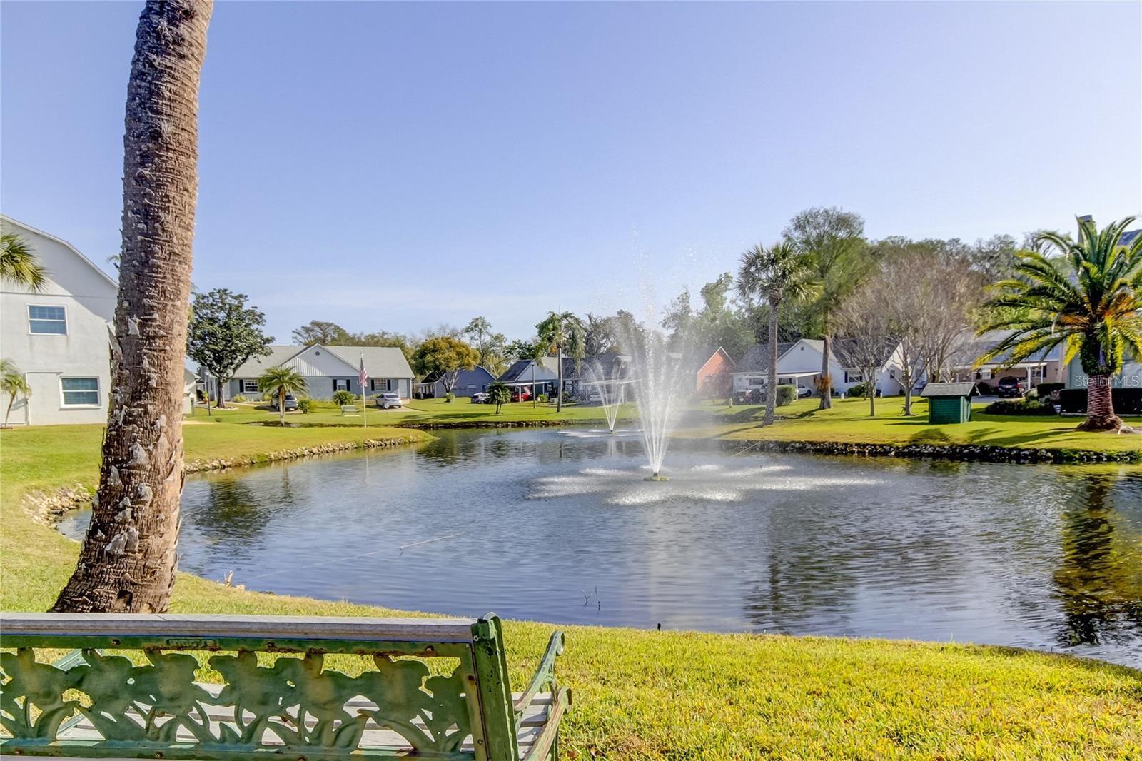A peaceful bench by a pond with gentle fountains.