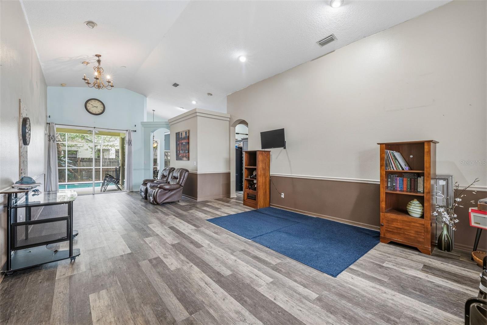 View of Formal Living Room/Dining Room from the front entry.  Looks straight to the backyard/pool. Notice the vaulted ceilings with recessed lighting and newer laminate flooring.