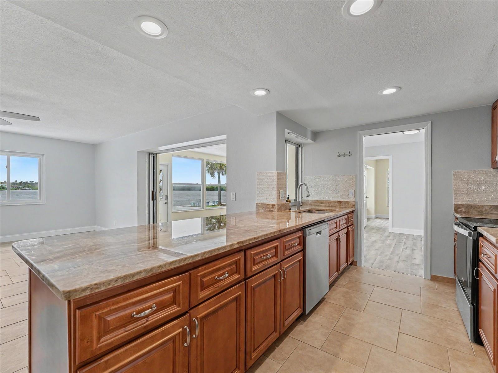 Updated Kitchen looking into the Family Room and Florida Room with spectacular views of the canal and Partial Gulf.