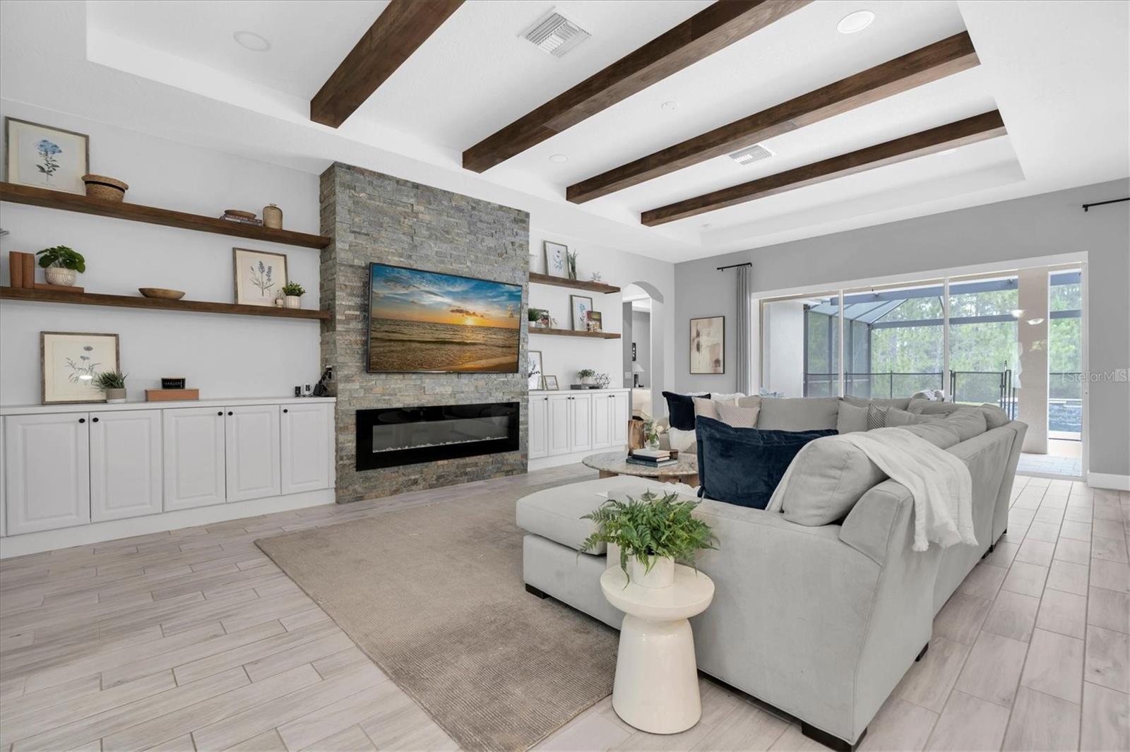 LIVING ROOM WITH STONE ACCENTWALL, WOOD BEAMS, FIREPLACE & CABINETS + DISPLAY SHELVES