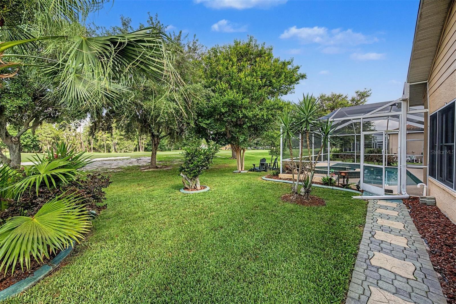 Lush, exterior back with thoughtful pavered walkway