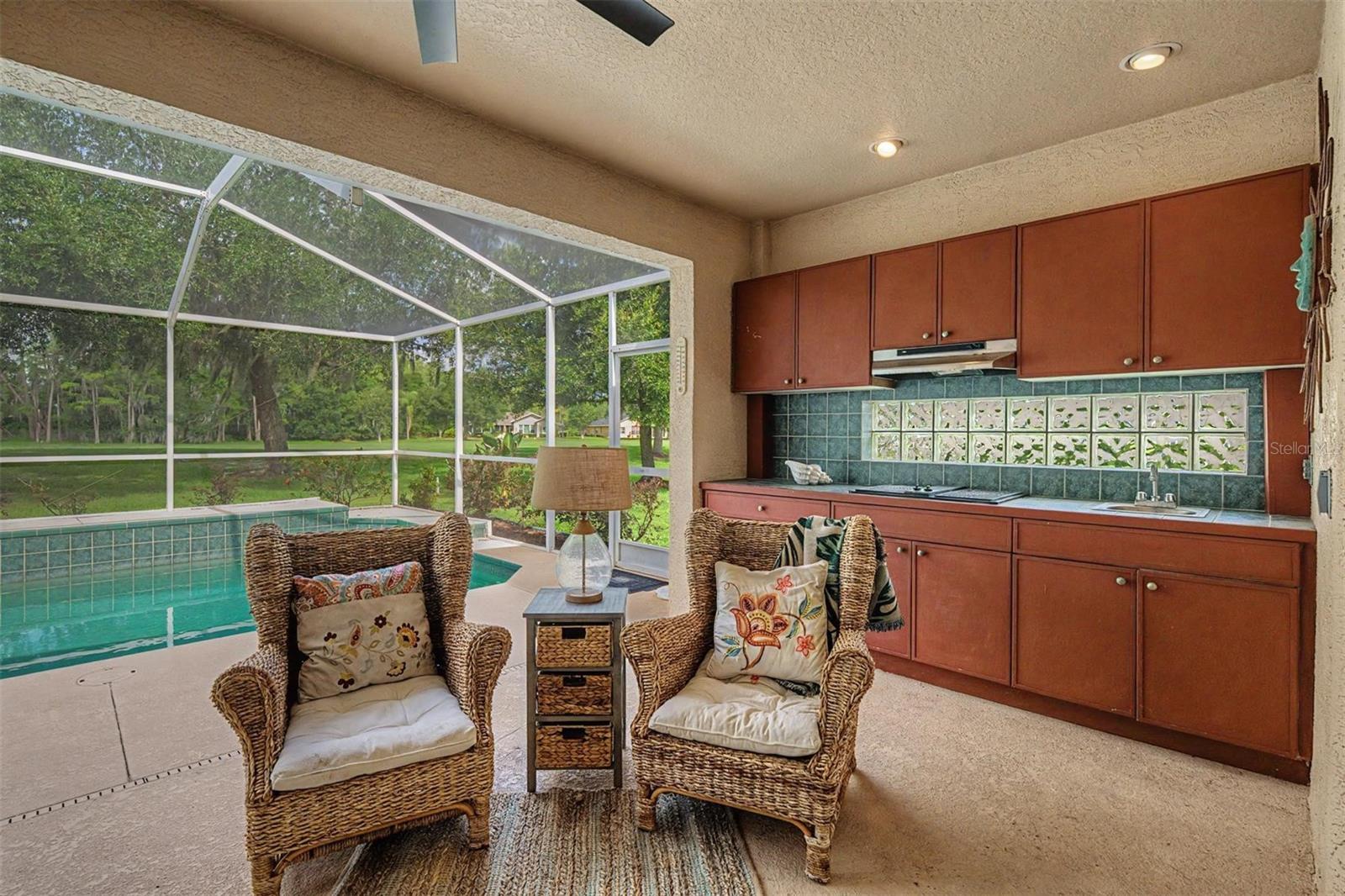 A true outdoor kitchen with cooktop and sink with custom cabinets and backsplash