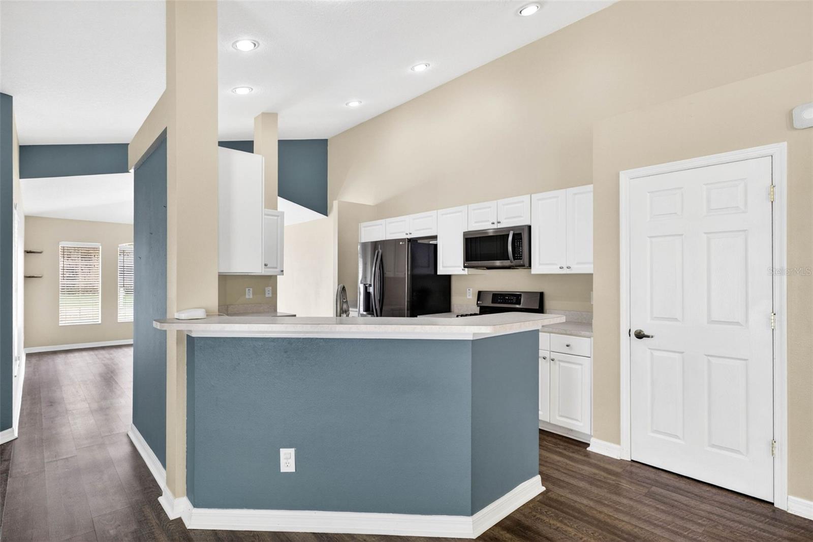 Kitchen with pantry, stainless steel appliances, & breakfast bar.