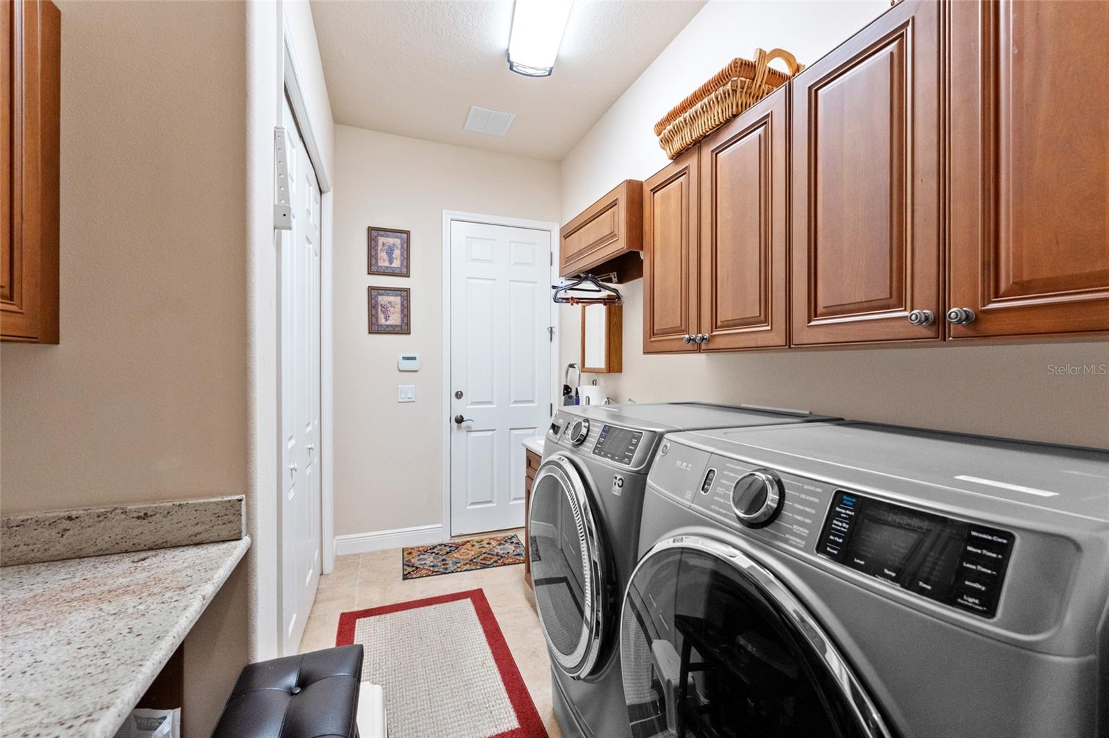 Laundry room with wood cabinetry, closet and folding station