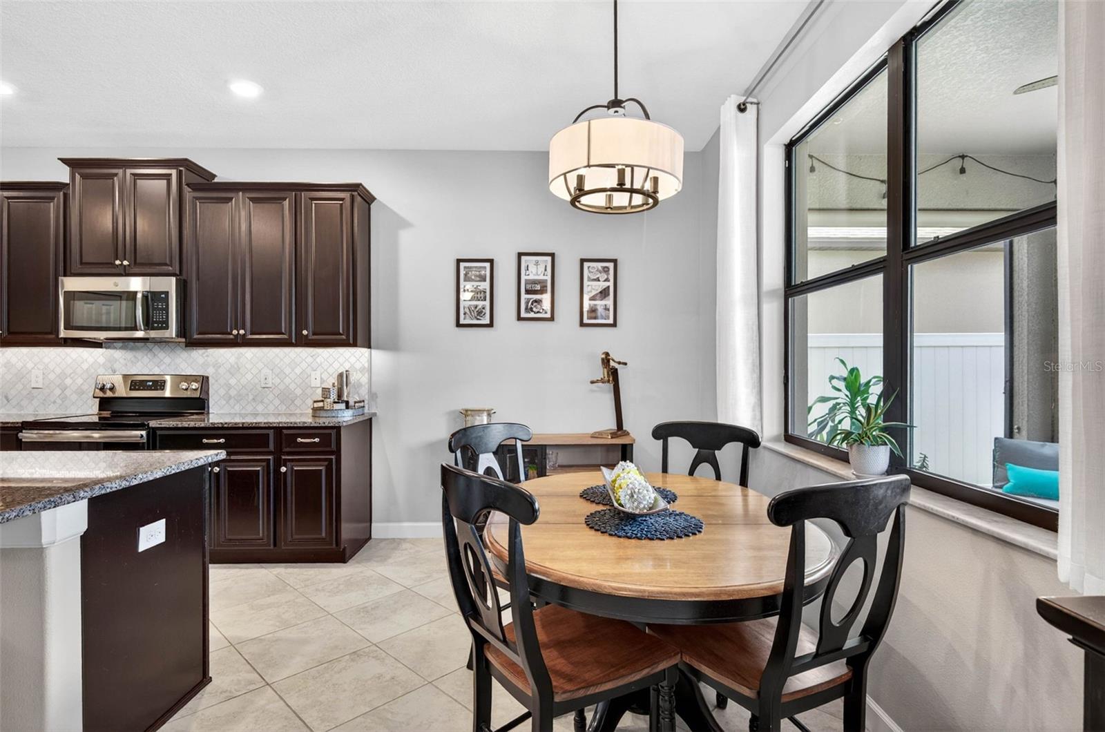 Breakfast nook off of kitchen area with large picture window overlooking screened lanai and fenced backyard