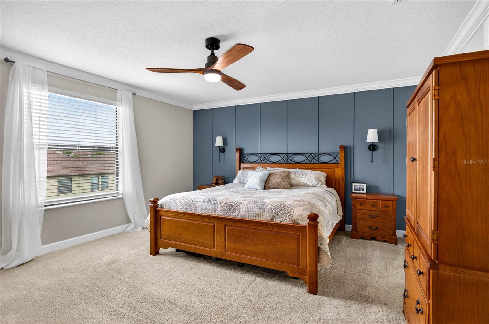 Primary bedroom located upstairs with large picture window overlooking the backyard with blinds and ceiling fan.