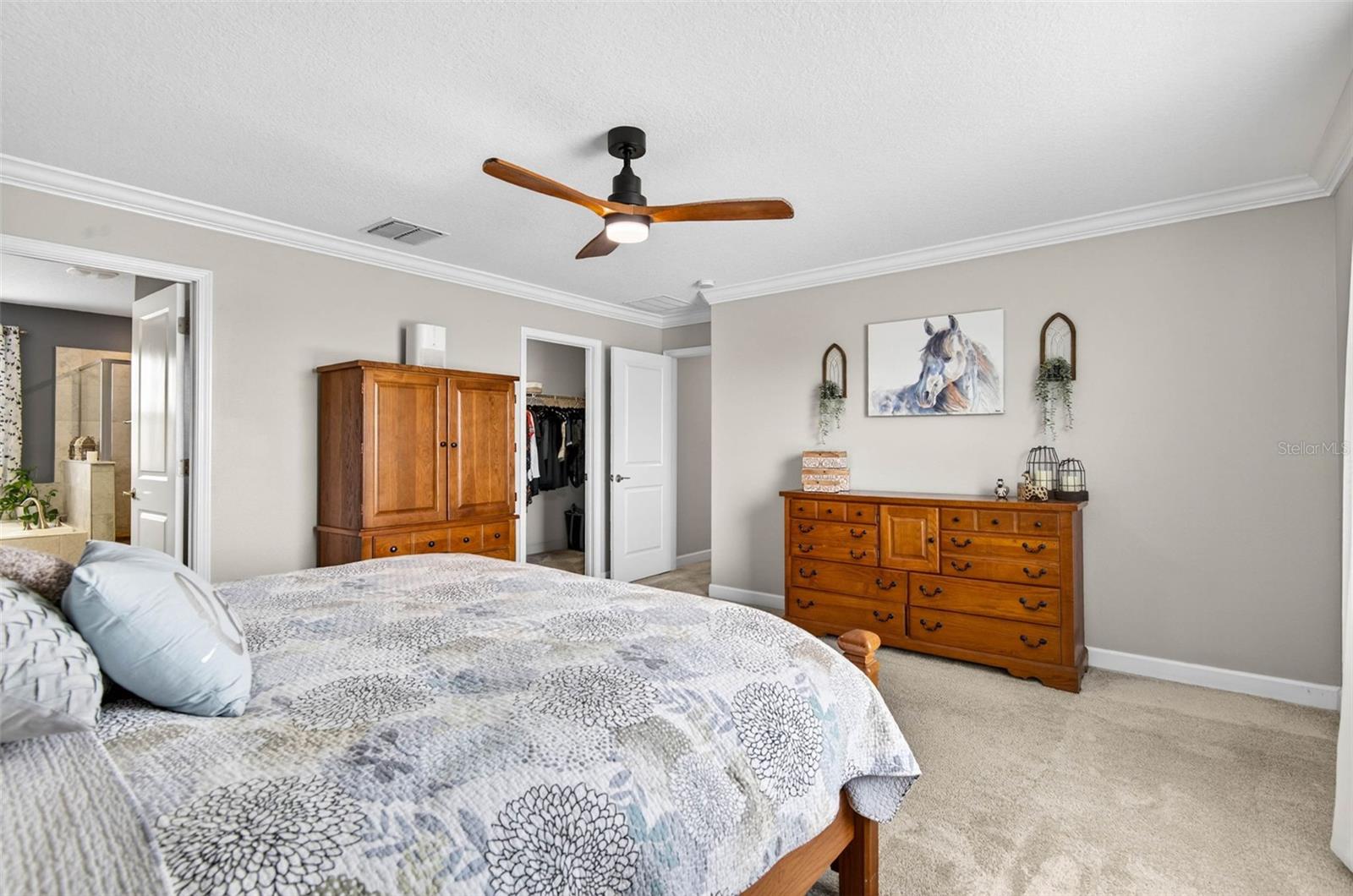 Primary bedroom with large walk in closet, ceiling fan and en suite bathroom
