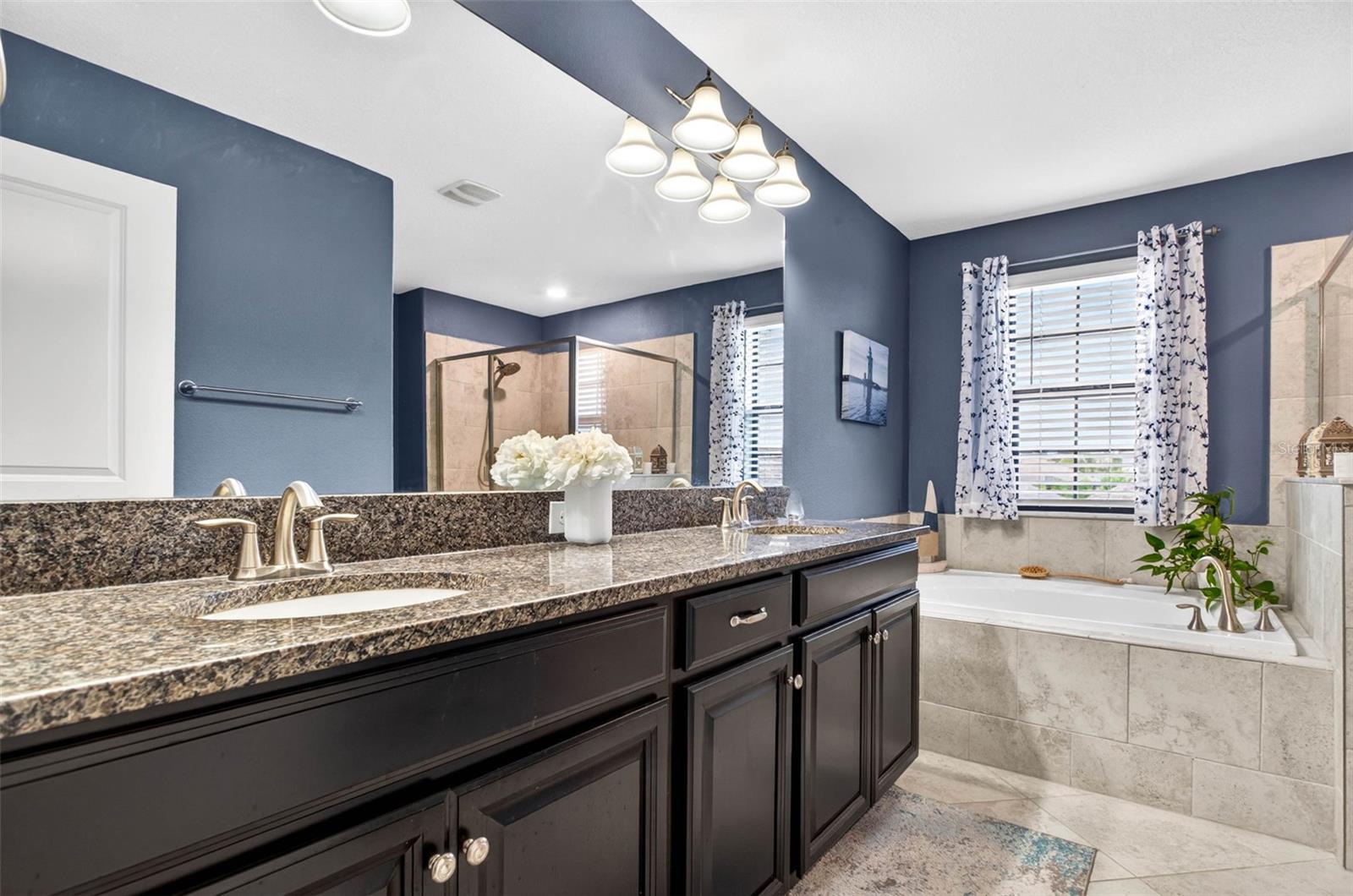 Primary bathroom with dual vanities, garden tub, walk in shower and blinds