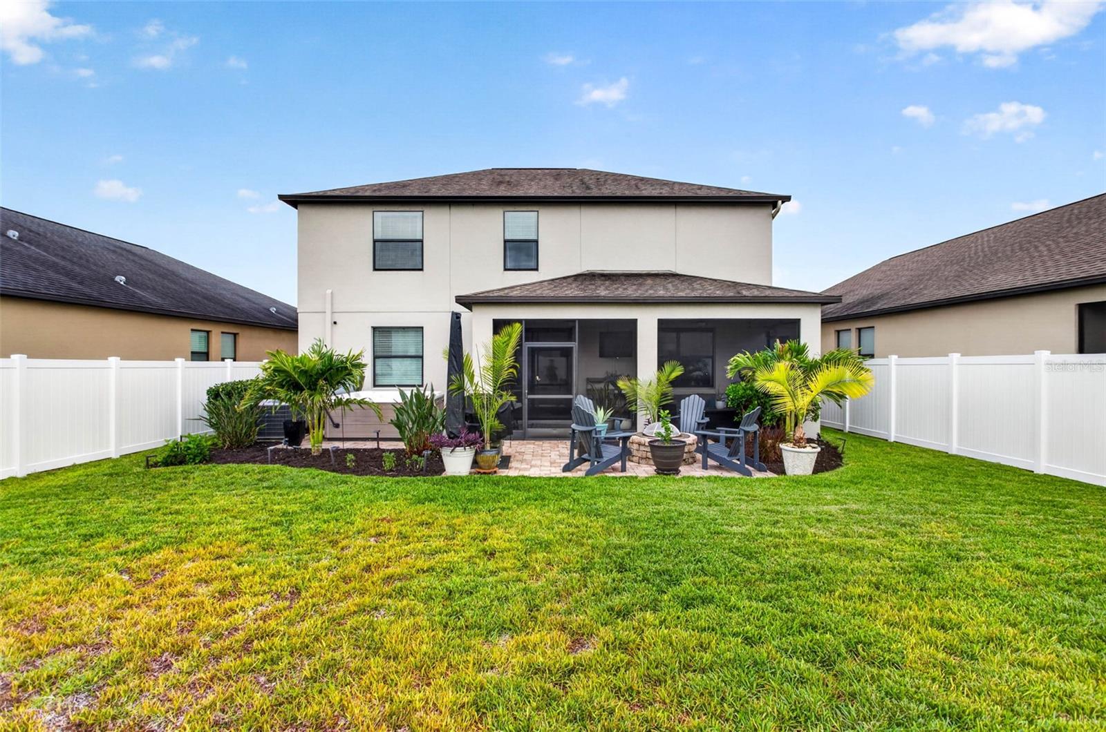 Fully fenced backyard and view of firepit and extended pavered area