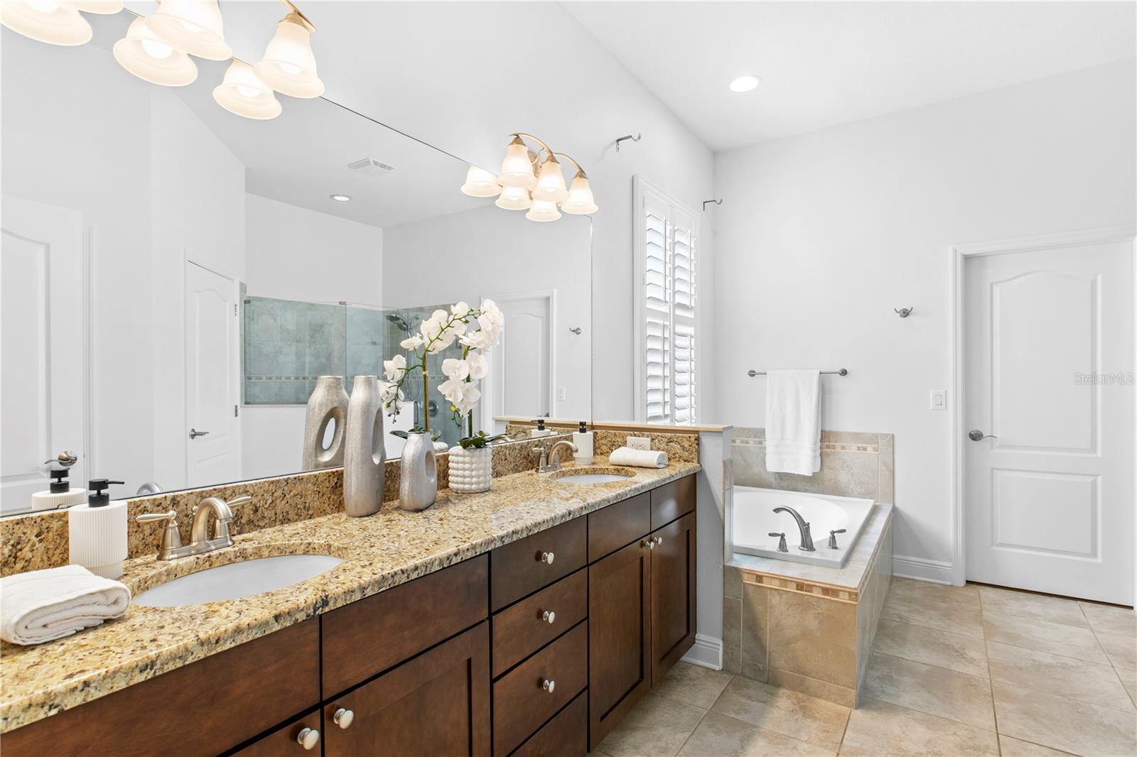 Spa-inspired en suite bath featuring dual vanities, and a generous walk-in closet