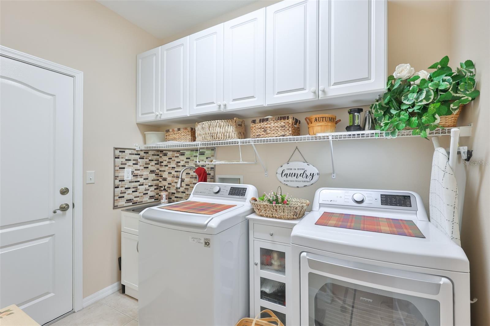 Laundry room with many cabinets and a nicestainless steel sink.