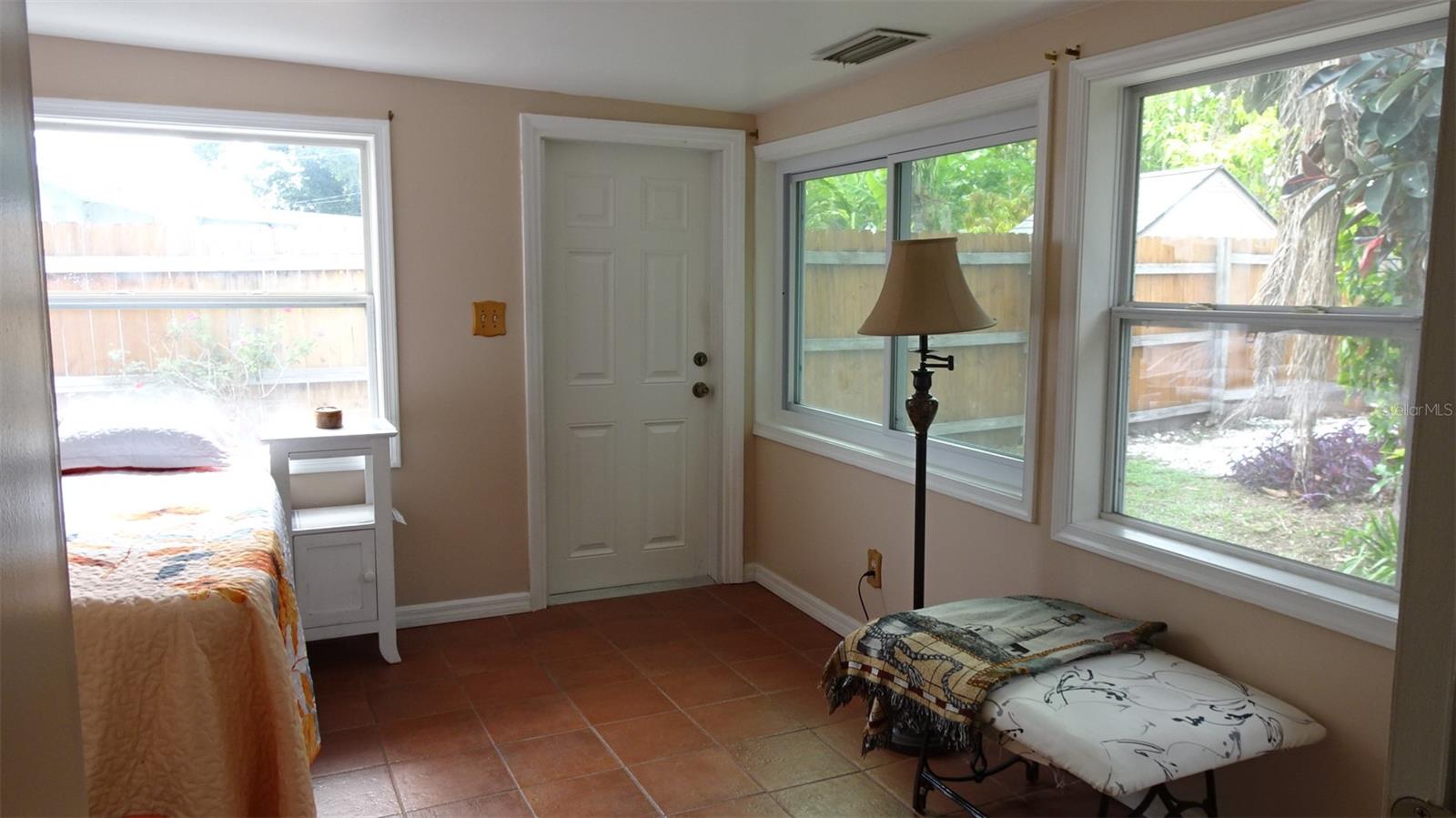 Bedroom #3, terra cotta tile floors, lots of light, rear door to exterior side yard.