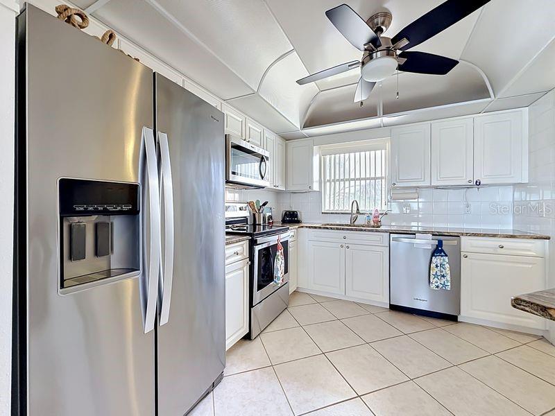 Modern coastal charm kitchen with tile floors, sleek finishes, and a layout that flows endlessly for entertaining.