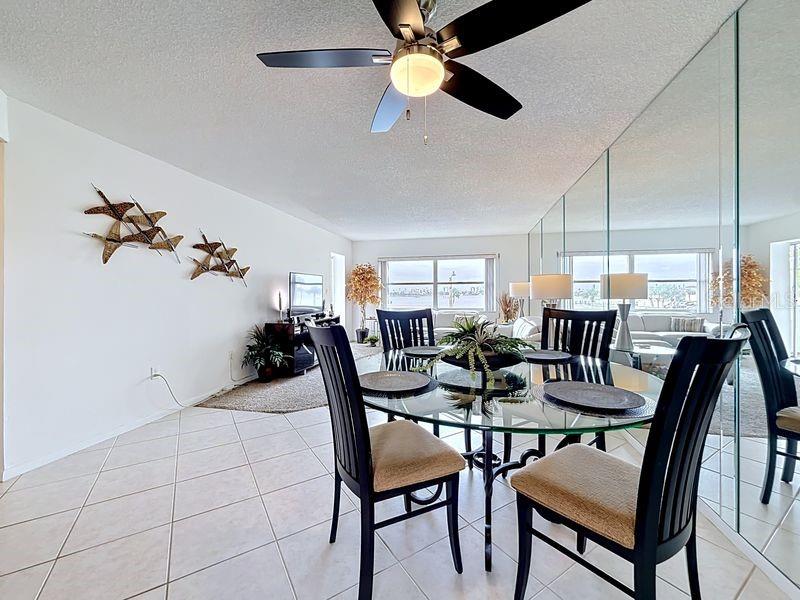 Open-concept dining area that flows seamlessly from the kitchen, featuring a glass-top table and modern coastal  decor.