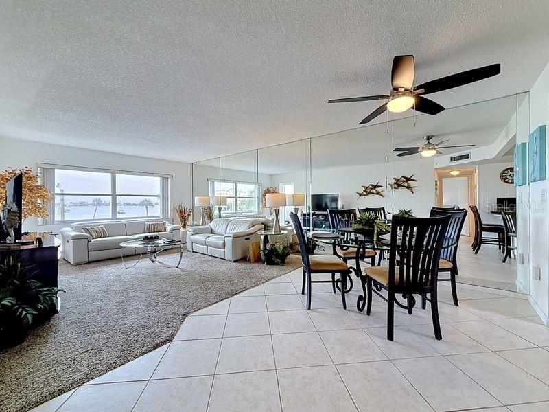 Open-concept dining area that flows seamlessly from the kitchen, featuring a glass-top table and modern coastal  decor.