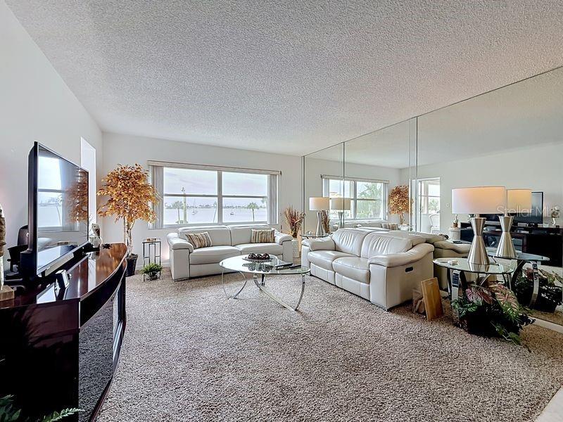 Open and airy living area that flows effortlessly from the dining room, highlighted by contemporary decor and warm sunlight and a serene view.