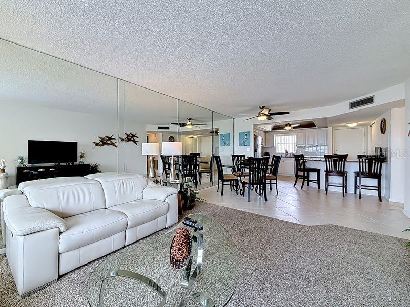 Open and airy living area that flows effortlessly from the dining room, highlighted by contemporary decor and warm sunlight and a serene view.