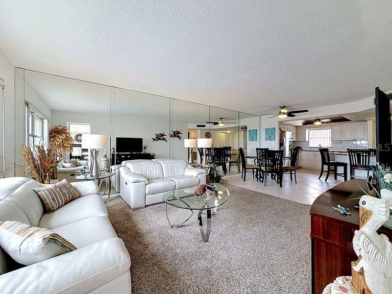 Open and airy living area that flows effortlessly from the dining room, highlighted by contemporary decor and warm sunlight and a serene view.
