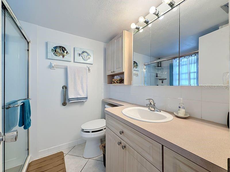 Inviting primary bathroom with warm wood cabinetry, soft lighting, and a relaxing coastal palette that ties the home's style together.
