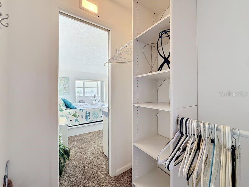 Organized walk-in closet featuring built-in shelving and plenty of hanging space