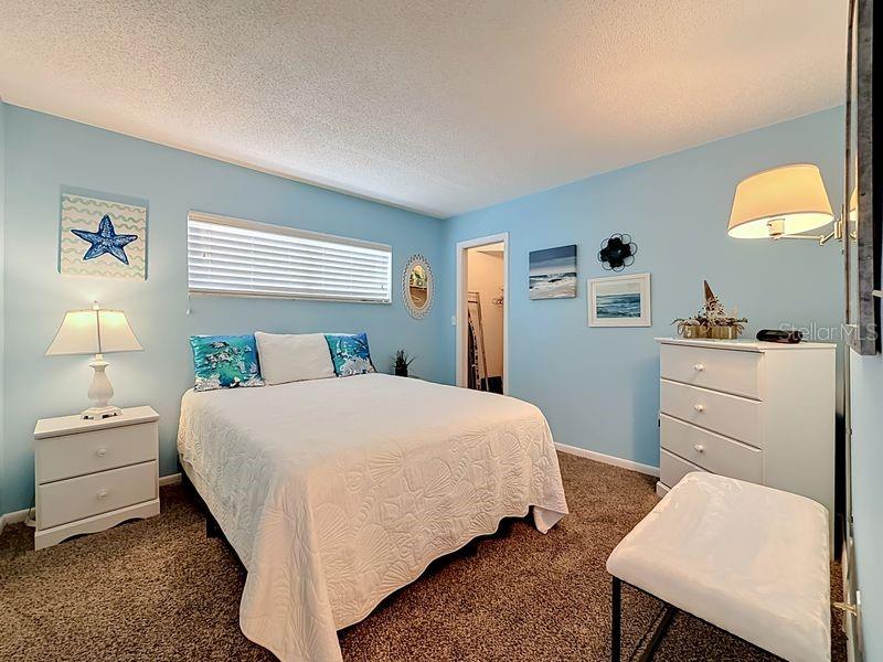 Cozy coastal guest room with soft blue walls, plush carpeting, and beach-inspired decor that creates a relaxing retreat.