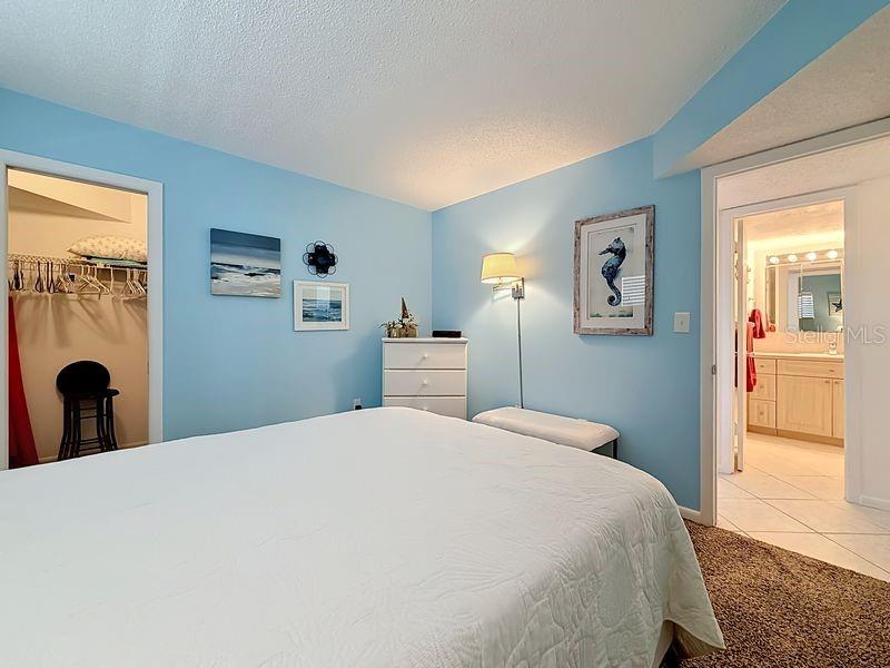 Cozy coastal guest room with soft blue walls, plush carpeting, and beach-inspired decor that creates a relaxing retreat.